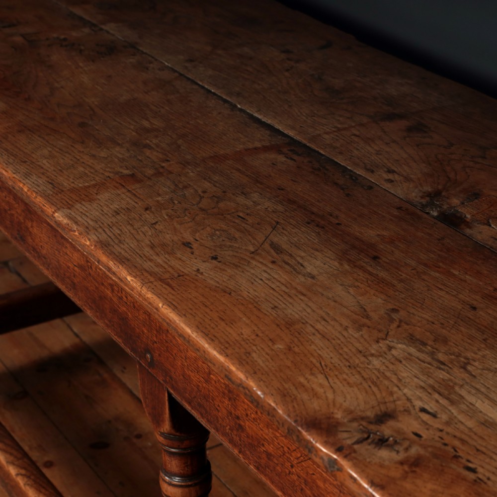 A long 17th-century oak refectory table featuring turned baluster legs, low stretchers, and a thick plank top. View VII