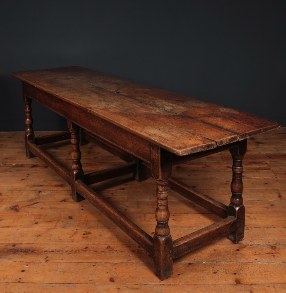 A long 17th-century oak refectory table featuring turned baluster legs, low stretchers, and a thick plank top. View IX