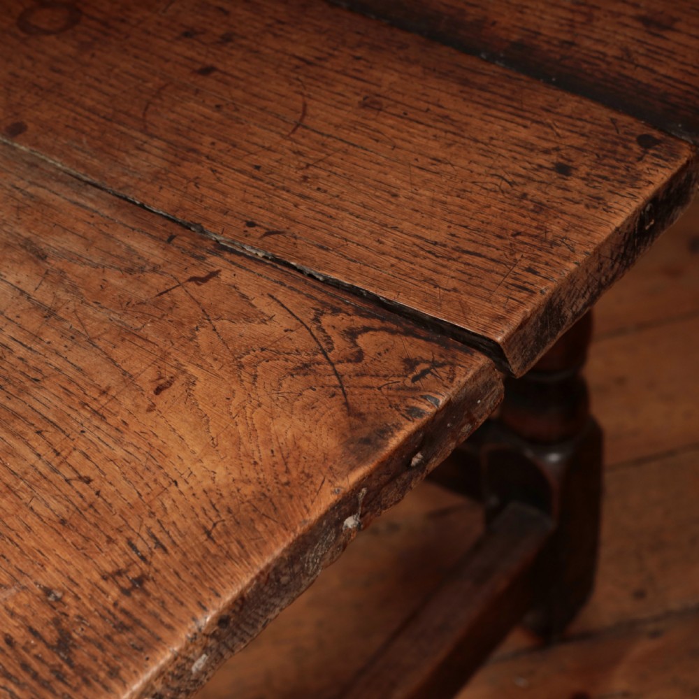 A long 17th-century oak refectory table featuring turned baluster legs, low stretchers, and a thick plank top. View X