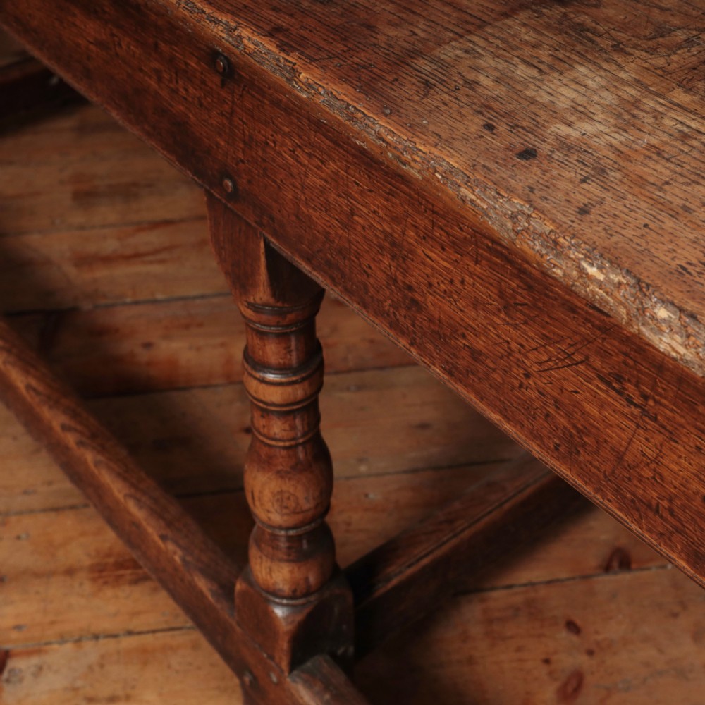 A long 17th-century oak refectory table featuring turned baluster legs, low stretchers, and a thick plank top. View XV