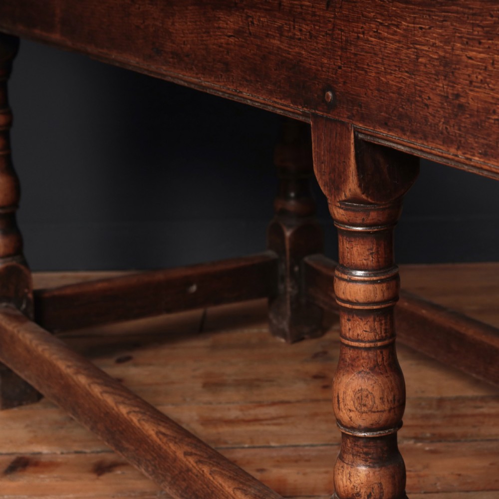 A long 17th-century oak refectory table featuring turned baluster legs, low stretchers, and a thick plank top. View XVI