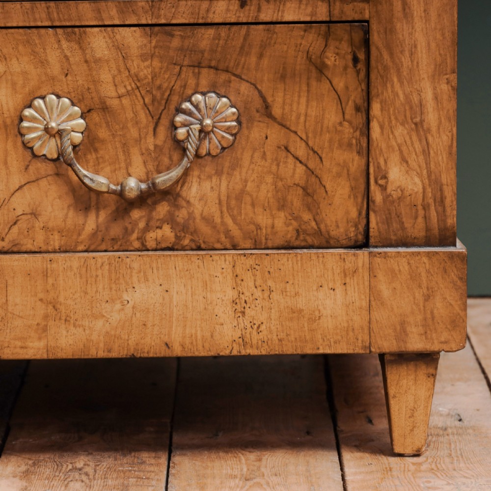 An 18th-century walnut commode featuring three wide drawers decorated with brass rosette swing handles and keyhole escutcheons on tapered feet. View III