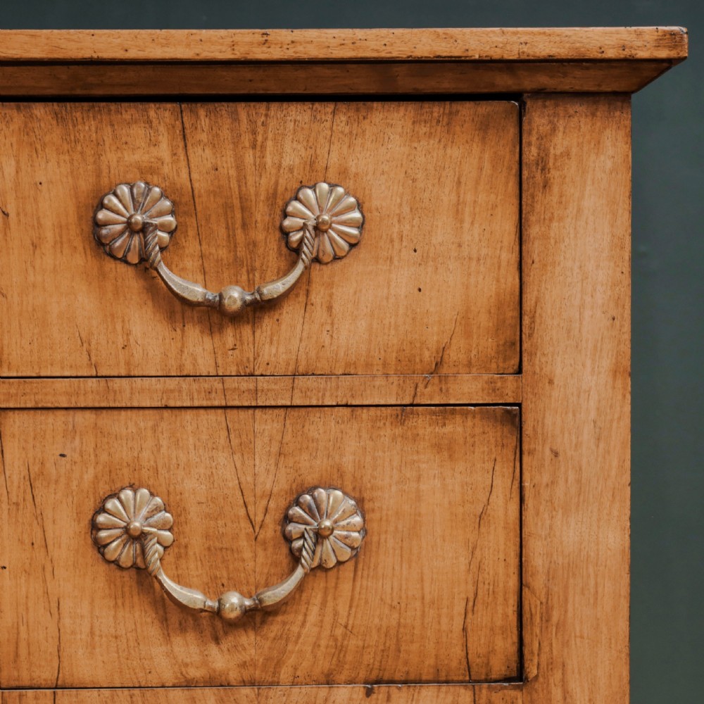 An 18th-century walnut commode featuring three wide drawers decorated with brass rosette swing handles and keyhole escutcheons on tapered feet. View VII