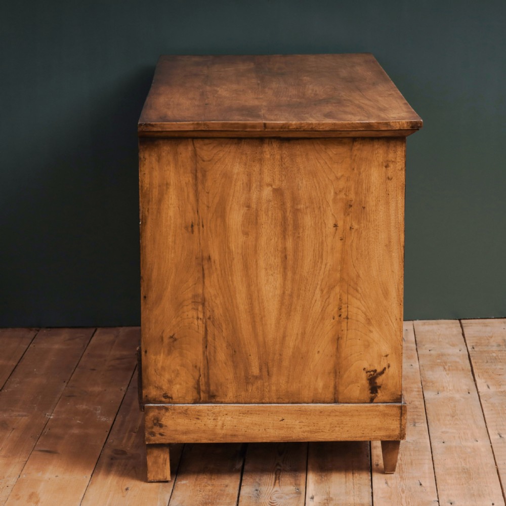 An 18th-century walnut commode featuring three wide drawers decorated with brass rosette swing handles and keyhole escutcheons on tapered feet. View VIII