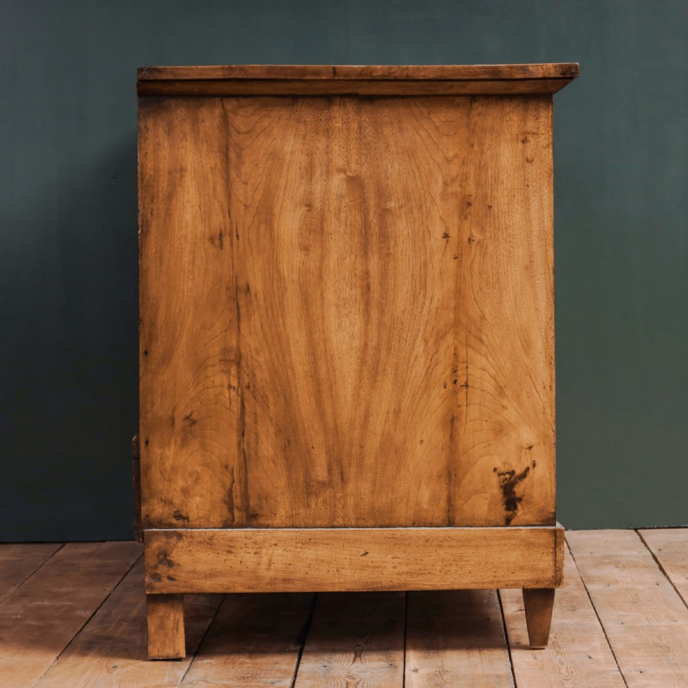 An 18th-century walnut commode featuring three wide drawers decorated with brass rosette swing handles and keyhole escutcheons on tapered feet. View IX