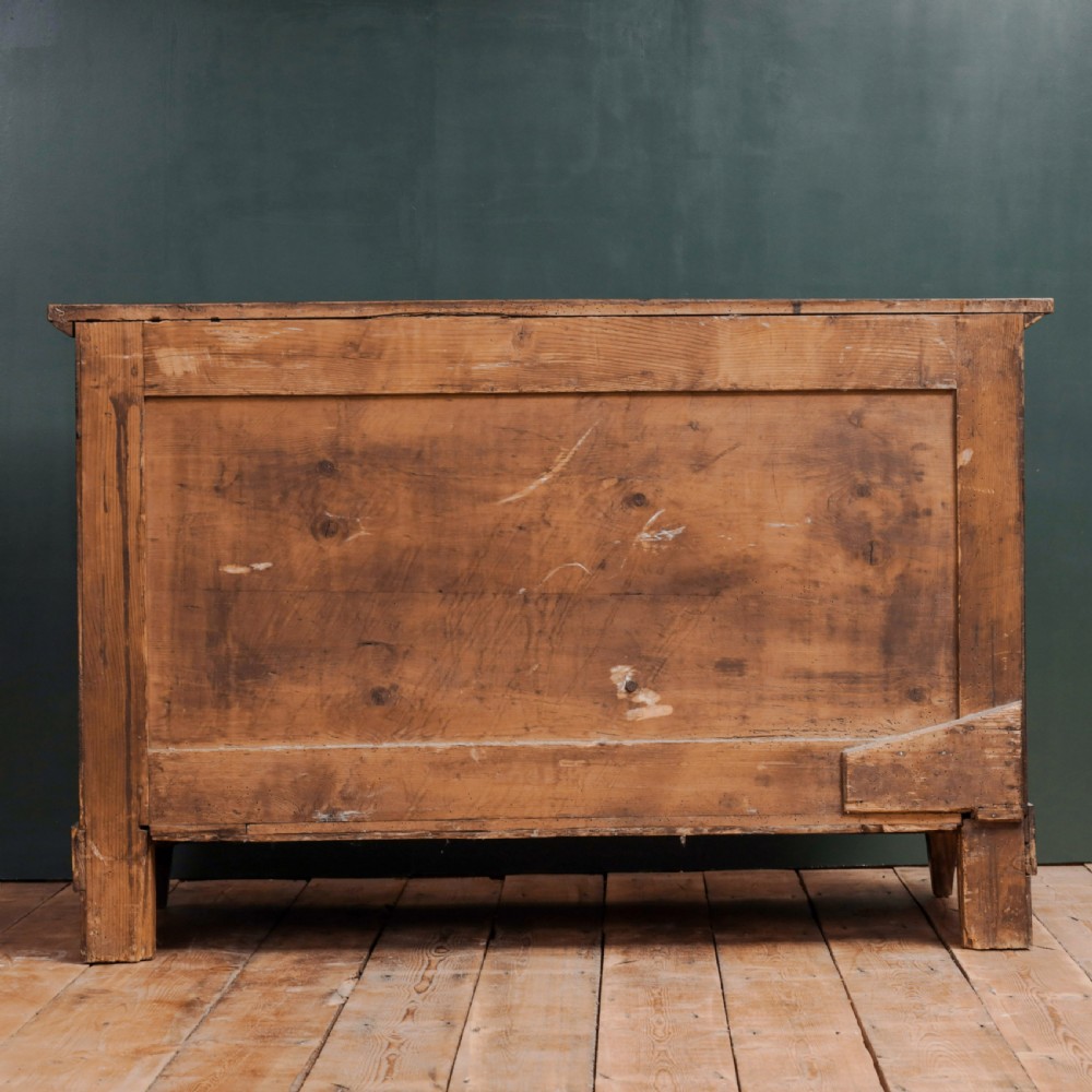 An 18th-century walnut commode featuring three wide drawers decorated with brass rosette swing handles and keyhole escutcheons on tapered feet. View X