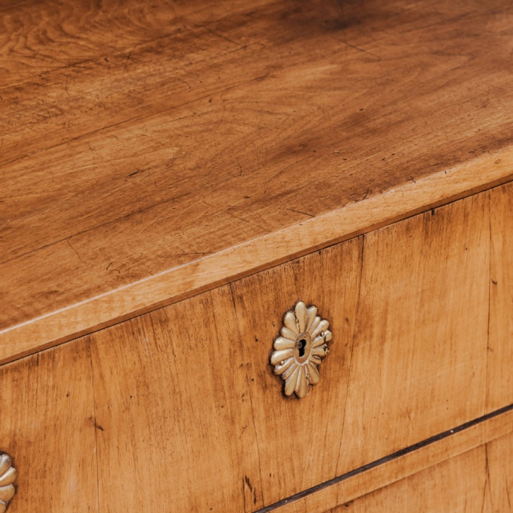 An 18th-century walnut commode featuring three wide drawers decorated with brass rosette swing handles and keyhole escutcheons on tapered feet. View XI
