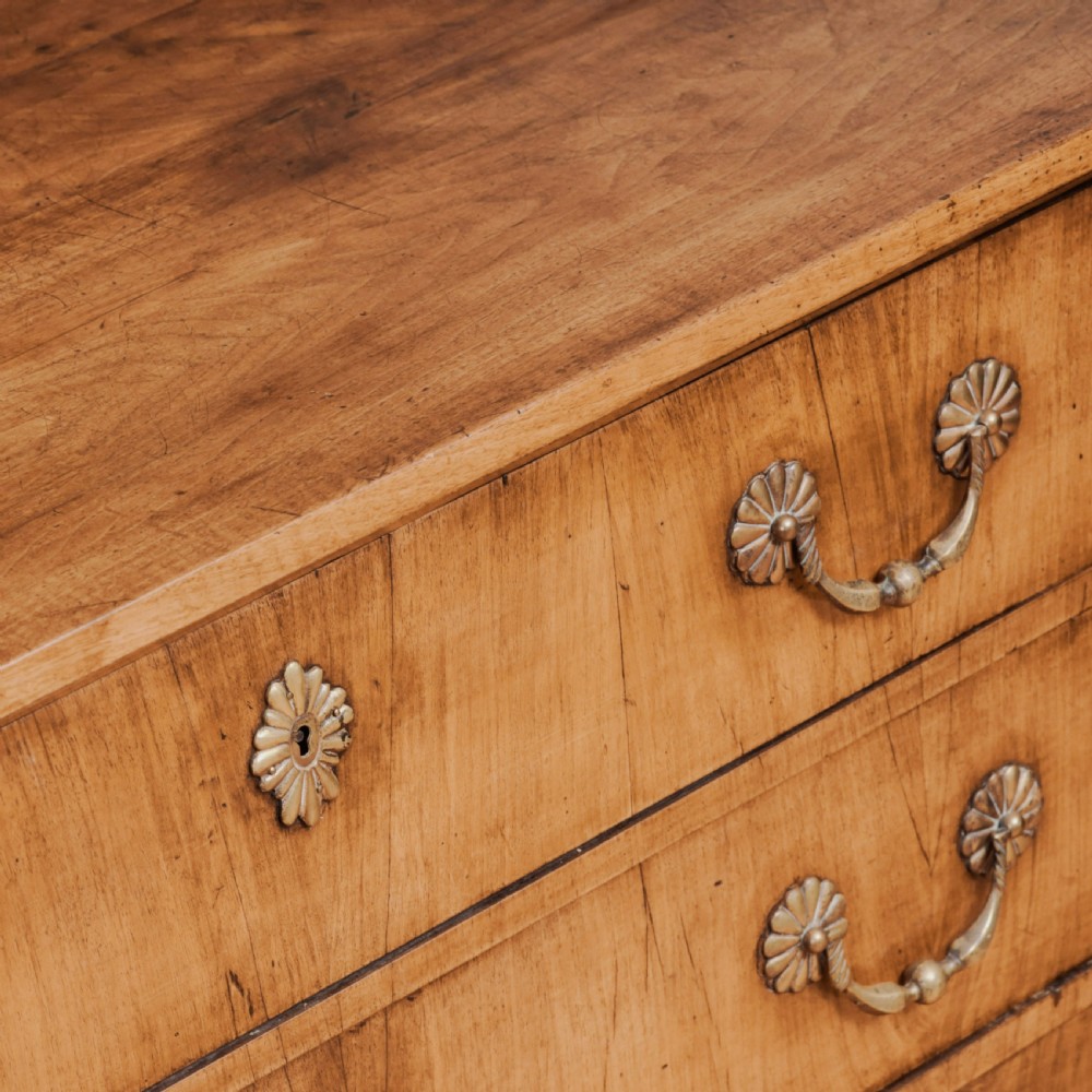 An 18th-century walnut commode featuring three wide drawers decorated with brass rosette swing handles and keyhole escutcheons on tapered feet. View XII