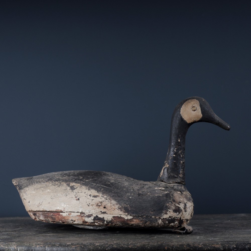 A 19th-century hand-carved wooden Canada goose decoy featuring distressed black and off-white paint with visible wear and natural patina. View IV