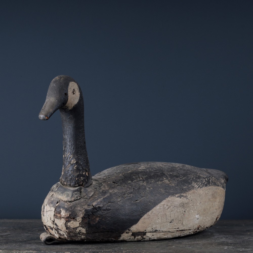 A 19th-century hand-carved wooden Canada goose decoy featuring distressed black and off-white paint with visible wear and natural patina. View V