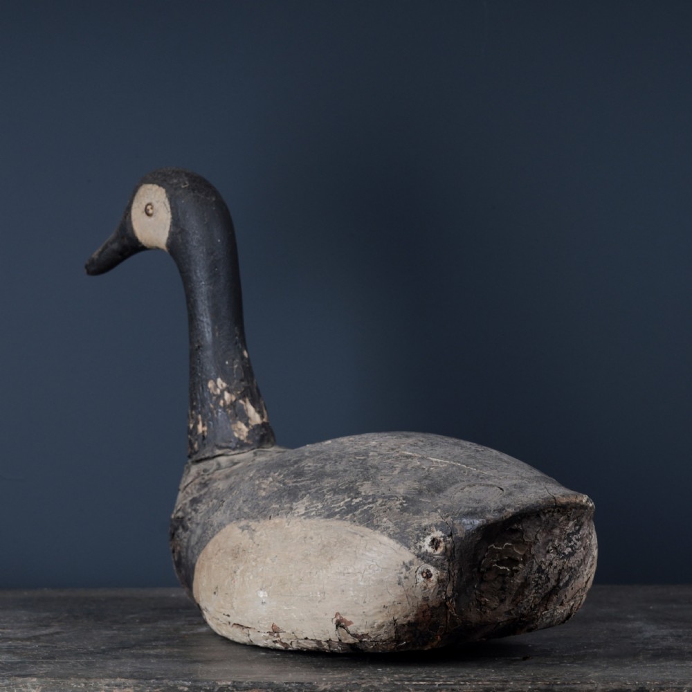 A 19th-century hand-carved wooden Canada goose decoy featuring distressed black and off-white paint with visible wear and natural patina. View VI