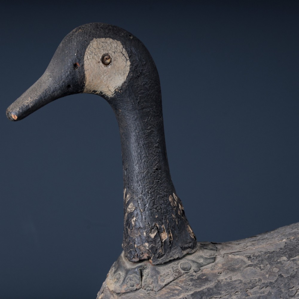 A 19th-century hand-carved wooden Canada goose decoy featuring distressed black and off-white paint with visible wear and natural patina. View VII