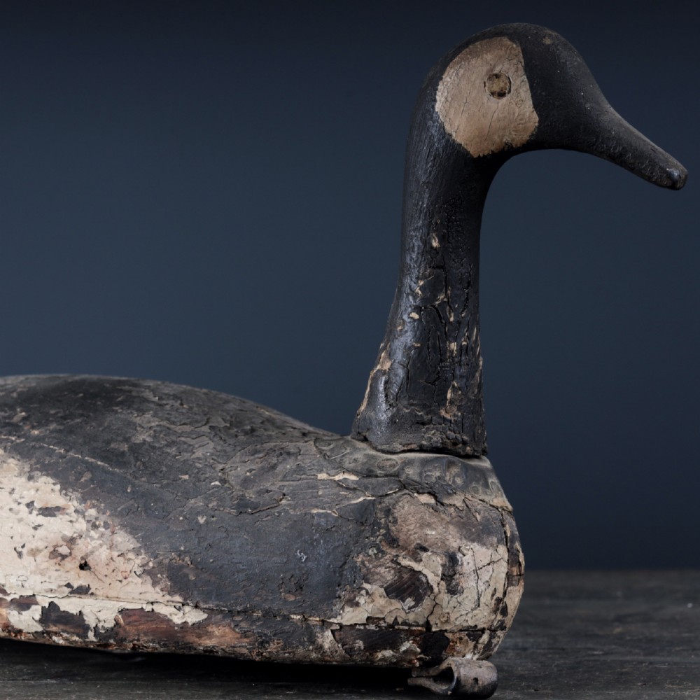 A 19th-century hand-carved wooden Canada goose decoy featuring distressed black and off-white paint with visible wear and natural patina. View IX