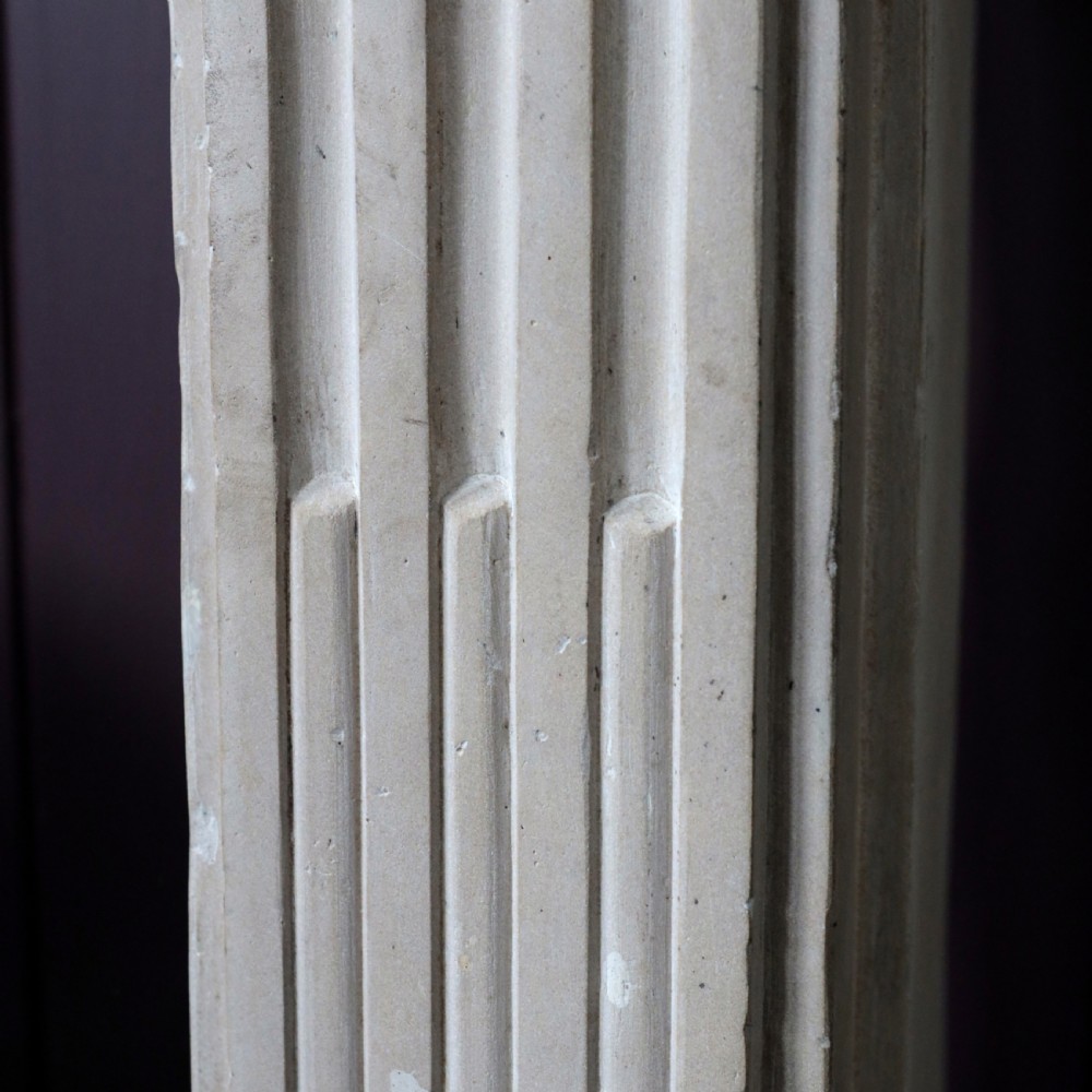 An off-white 18th-century stone fire surround featuring fluted pilasters, floral corner rosettes, and a moulded mantelshelf. View IX