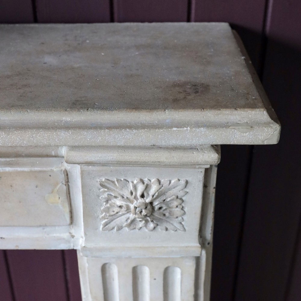 An off-white 18th-century stone fire surround featuring fluted pilasters, floral corner rosettes, and a moulded mantelshelf. View X