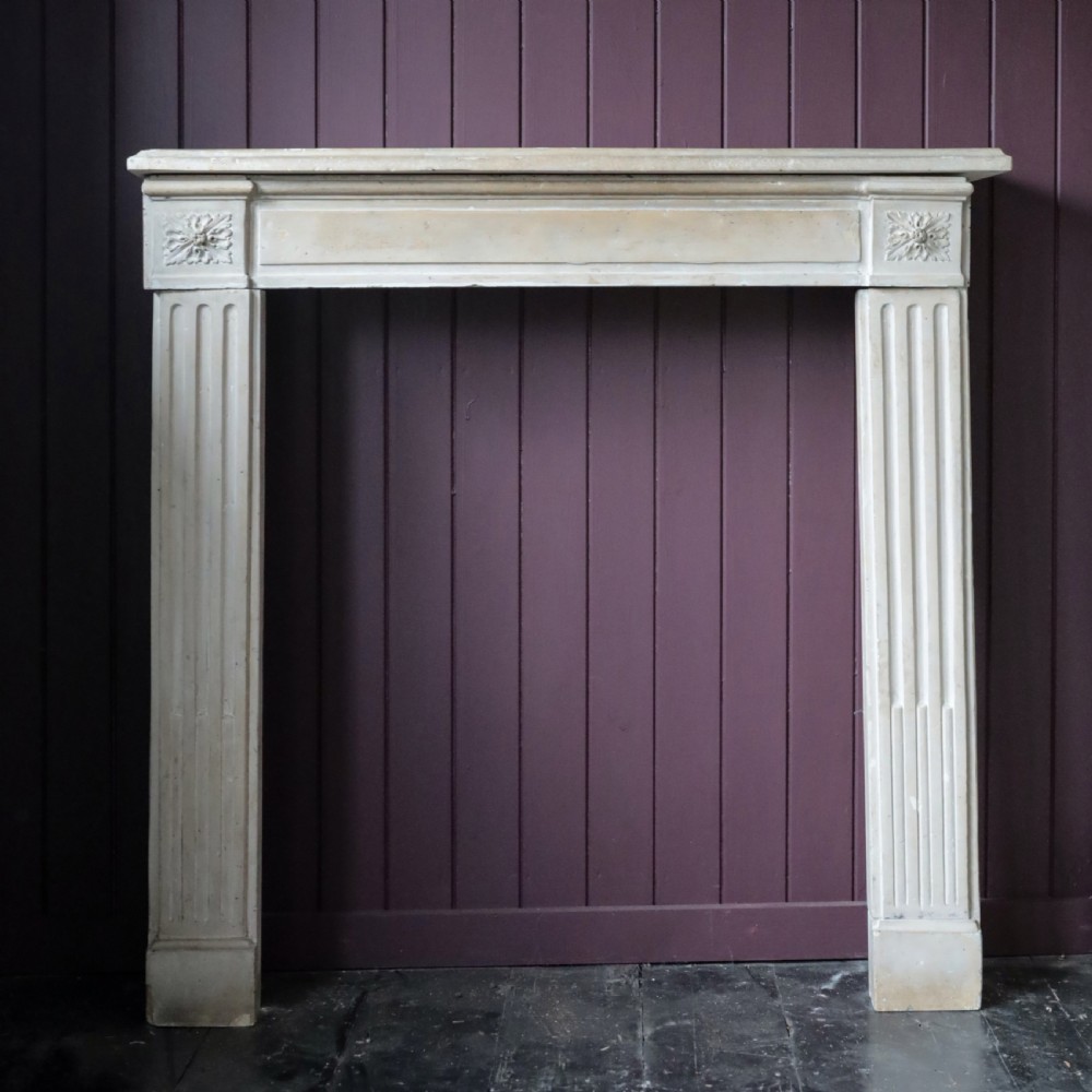 An off-white 18th-century stone fire surround featuring fluted pilasters, floral corner rosettes, and a moulded mantelshelf. View XI
