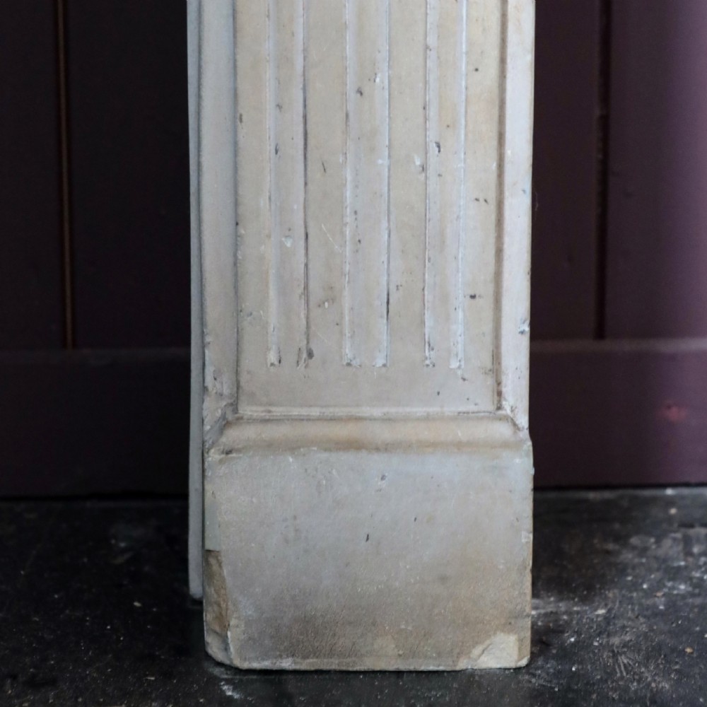 An off-white 18th-century stone fire surround featuring fluted pilasters, floral corner rosettes, and a moulded mantelshelf. View XIV