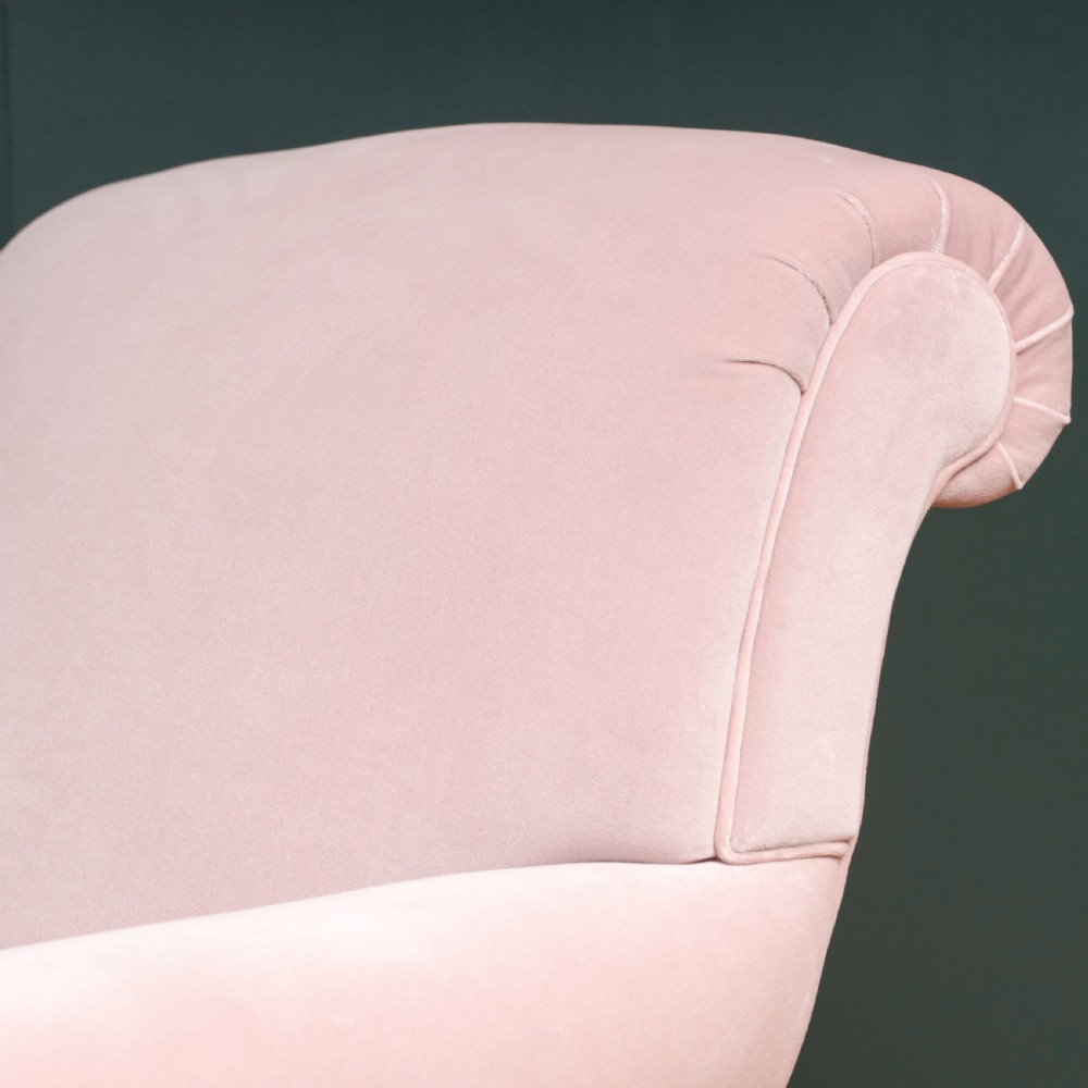 A 19th-century low-slung armchair upholstered in pale pink velvet, featuring rolled arms, a scrolled back, and turned front legs on brass castors. View III