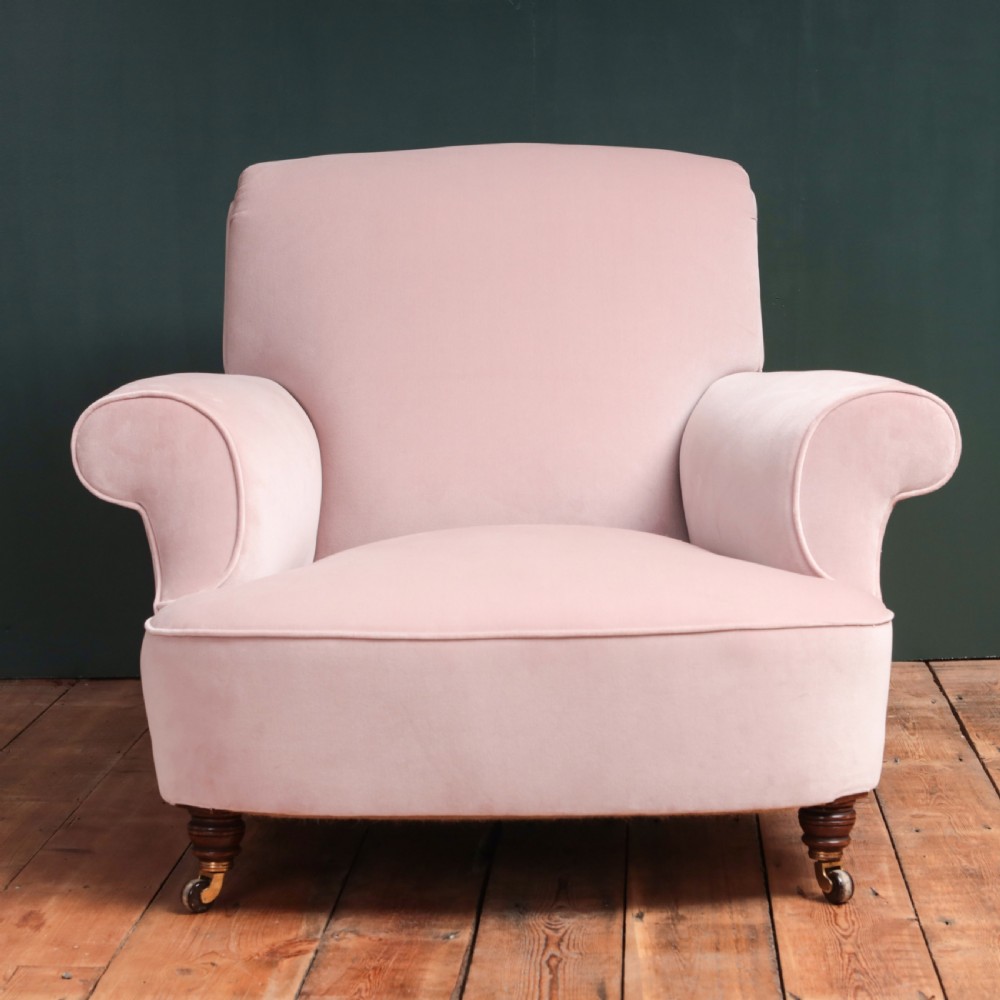 A 19th-century low-slung armchair upholstered in pale pink velvet, featuring rolled arms, a scrolled back, and turned front legs on brass castors. View VII