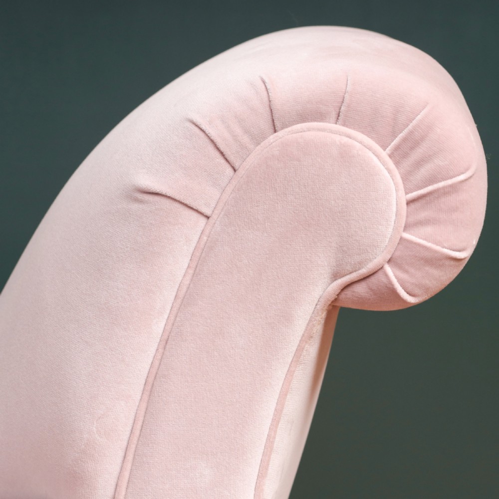 A 19th-century low-slung armchair upholstered in pale pink velvet, featuring rolled arms, a scrolled back, and turned front legs on brass castors. View X