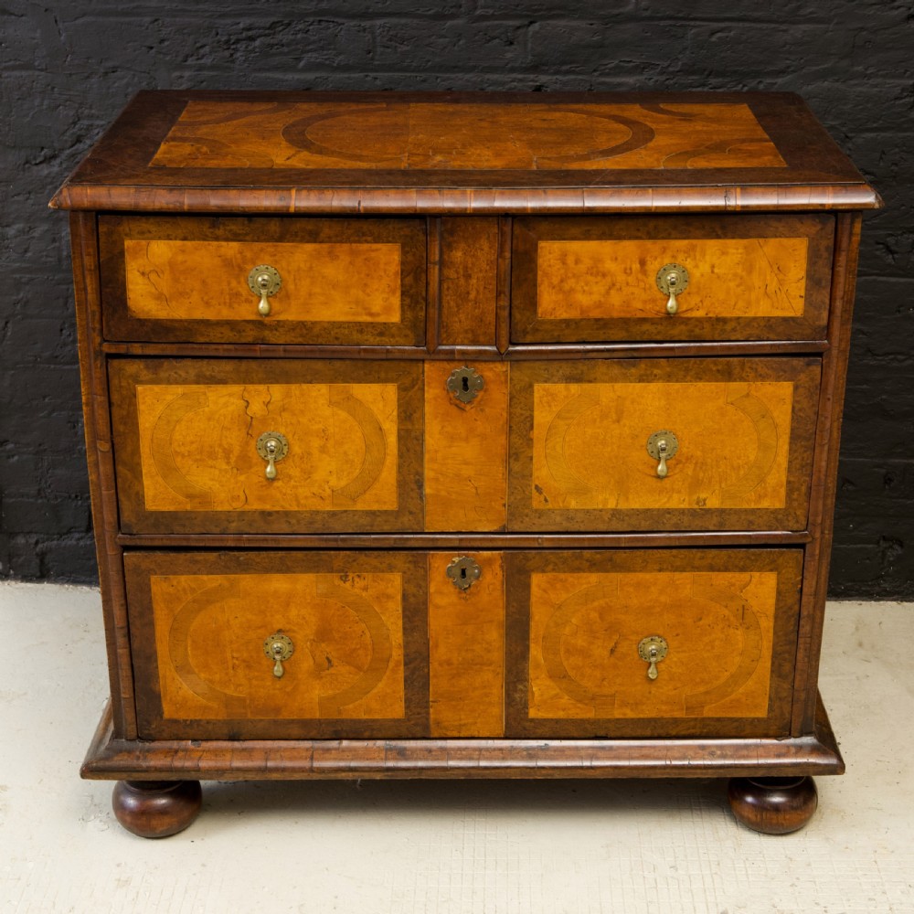 A late 17th-century William and Mary chest of drawers crafted from yew and maple featuring geometric inlaid panels, teardrop brass handles, and turned bun feet. View II