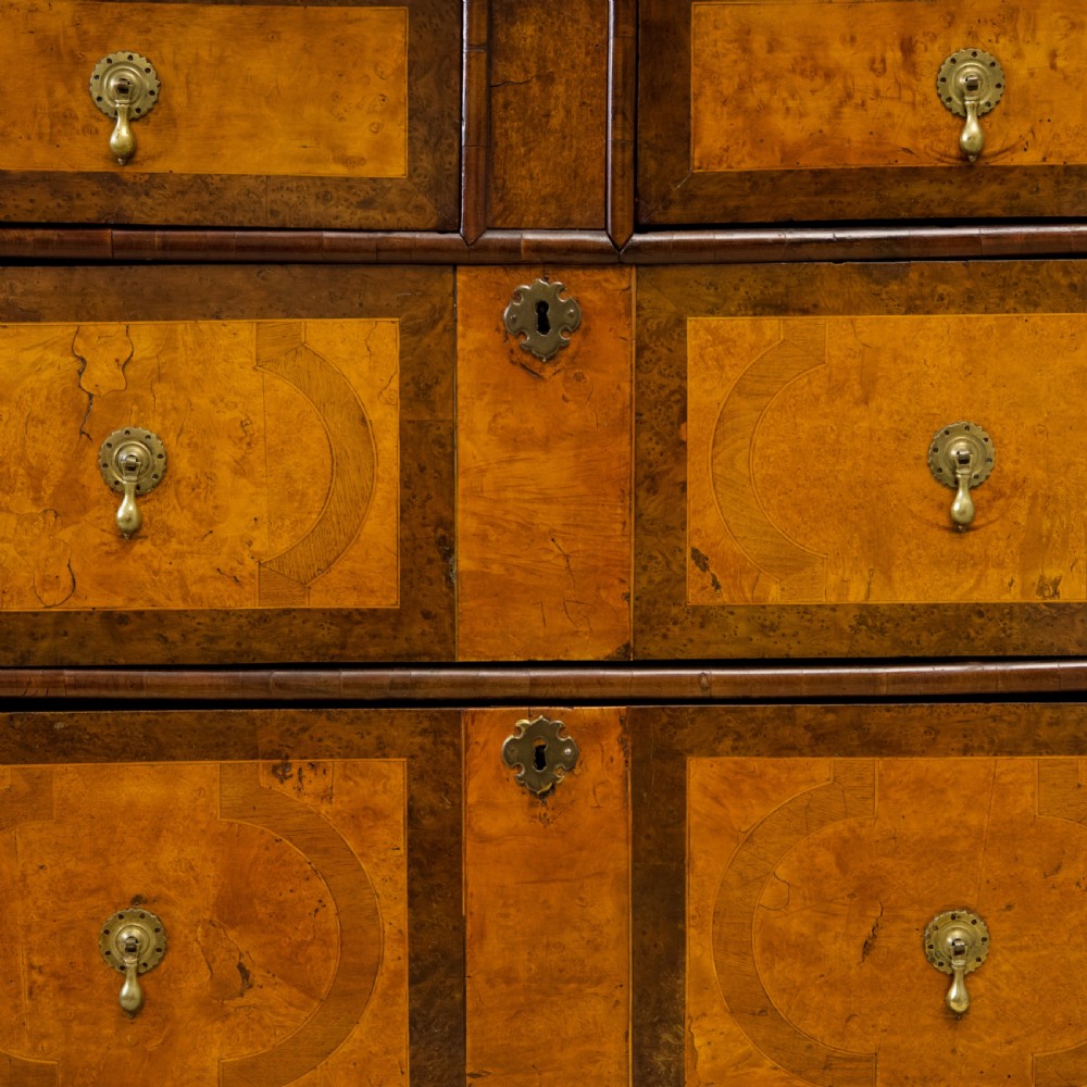 A late 17th-century William and Mary chest of drawers crafted from yew and maple featuring geometric inlaid panels, teardrop brass handles, and turned bun feet. View III
