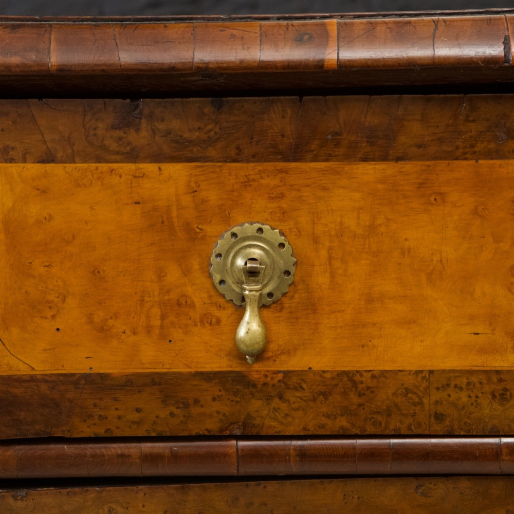 A late 17th-century William and Mary chest of drawers crafted from yew and maple featuring geometric inlaid panels, teardrop brass handles, and turned bun feet. View IV