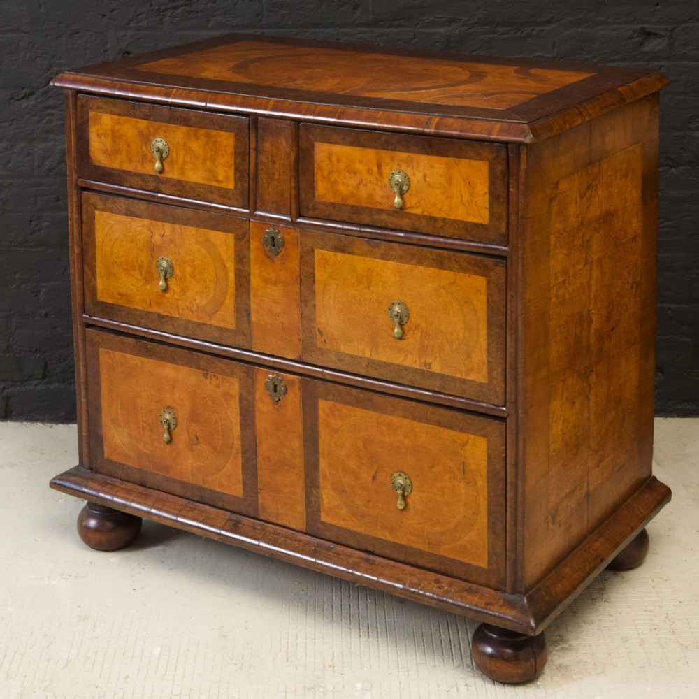 A late 17th-century William and Mary chest of drawers crafted from yew and maple featuring geometric inlaid panels, teardrop brass handles, and turned bun feet. View VIII