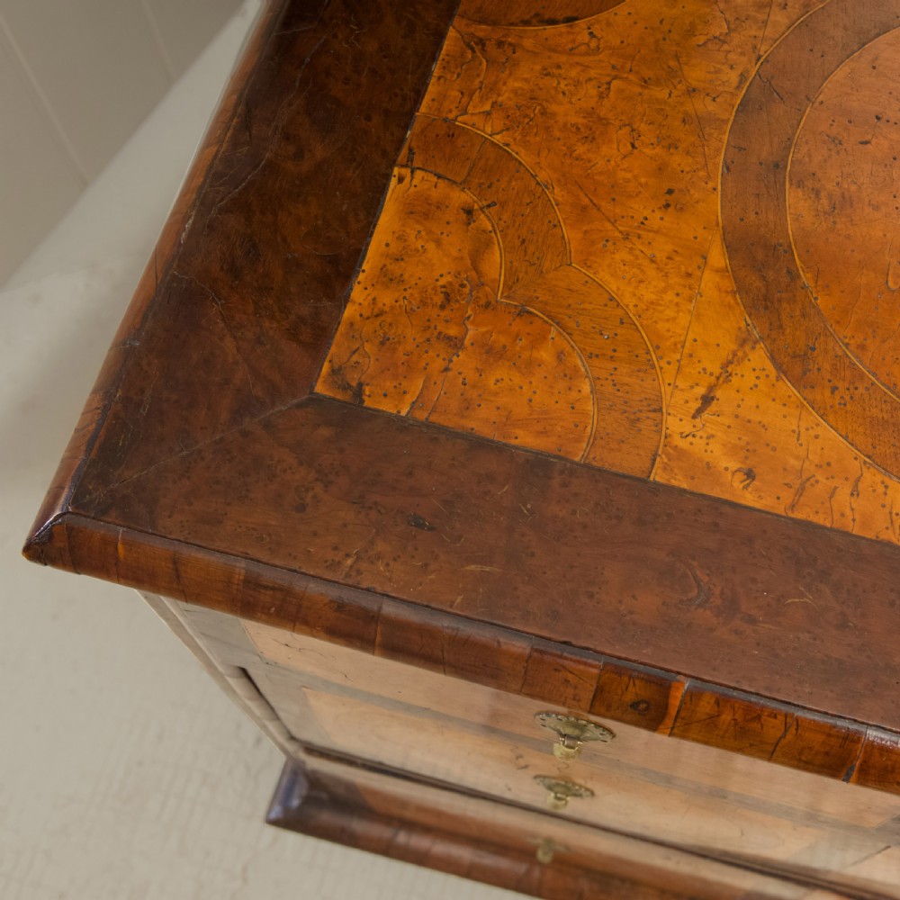 A late 17th-century William and Mary chest of drawers crafted from yew and maple featuring geometric inlaid panels, teardrop brass handles, and turned bun feet. View IX