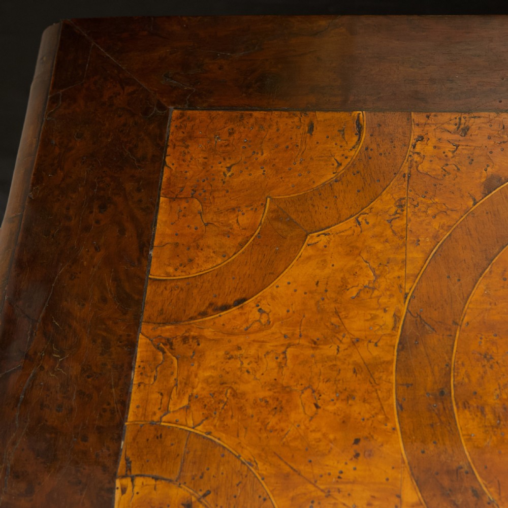A late 17th-century William and Mary chest of drawers crafted from yew and maple featuring geometric inlaid panels, teardrop brass handles, and turned bun feet. View X