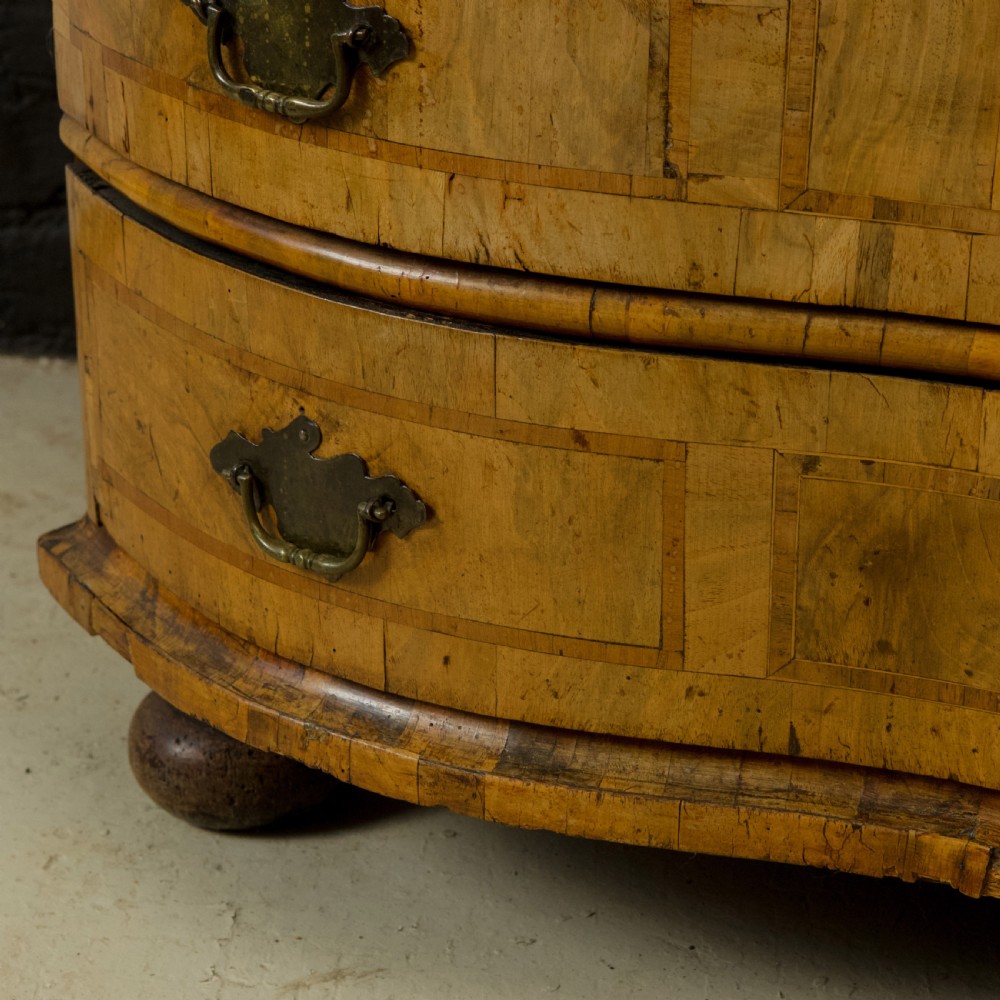 An 18th-century South German walnut chest of drawers featuring a serpentine front, four crossbanded drawers, brass drop handles, and turned bun feet. View IV