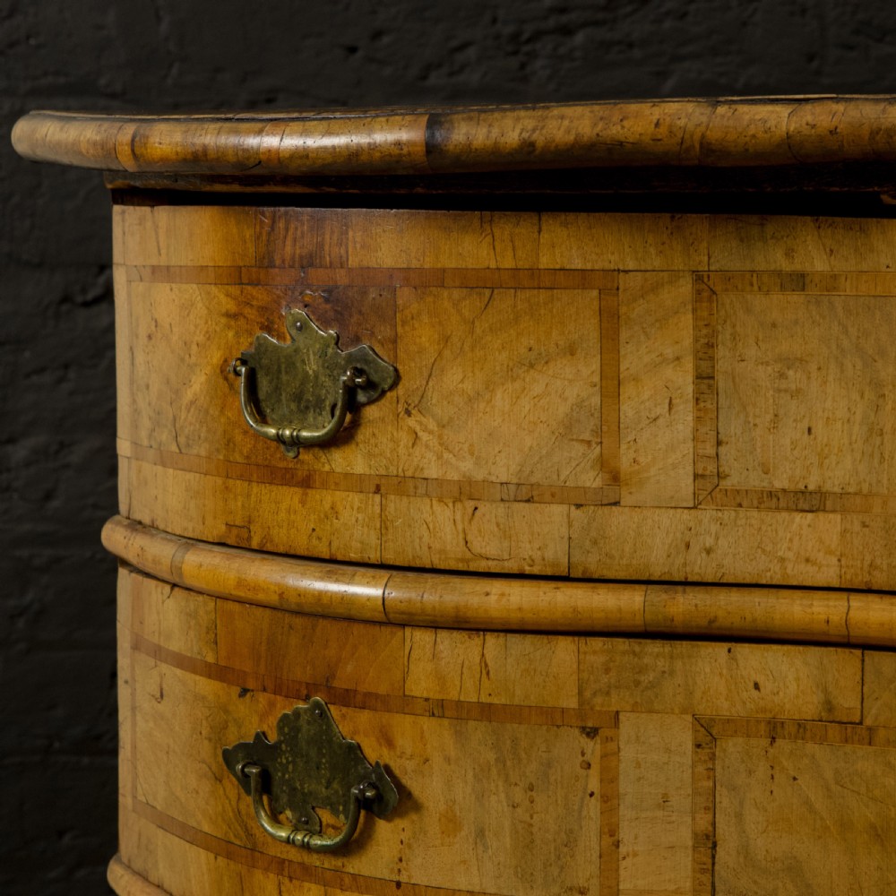 An 18th-century South German walnut chest of drawers featuring a serpentine front, four crossbanded drawers, brass drop handles, and turned bun feet. View VI