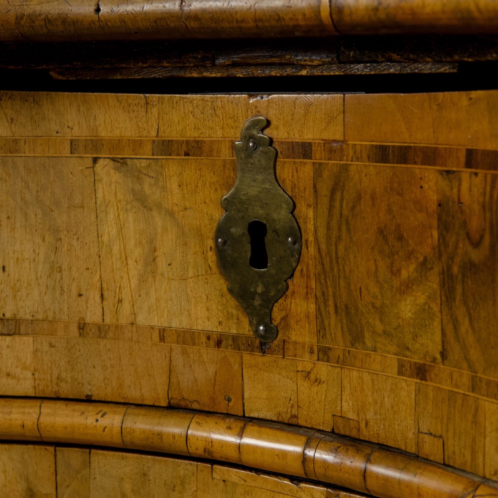 An 18th-century South German walnut chest of drawers featuring a serpentine front, four crossbanded drawers, brass drop handles, and turned bun feet. View XI