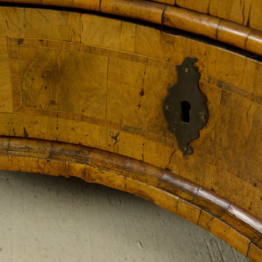 An 18th-century South German walnut chest of drawers featuring a serpentine front, four crossbanded drawers, brass drop handles, and turned bun feet. View XII