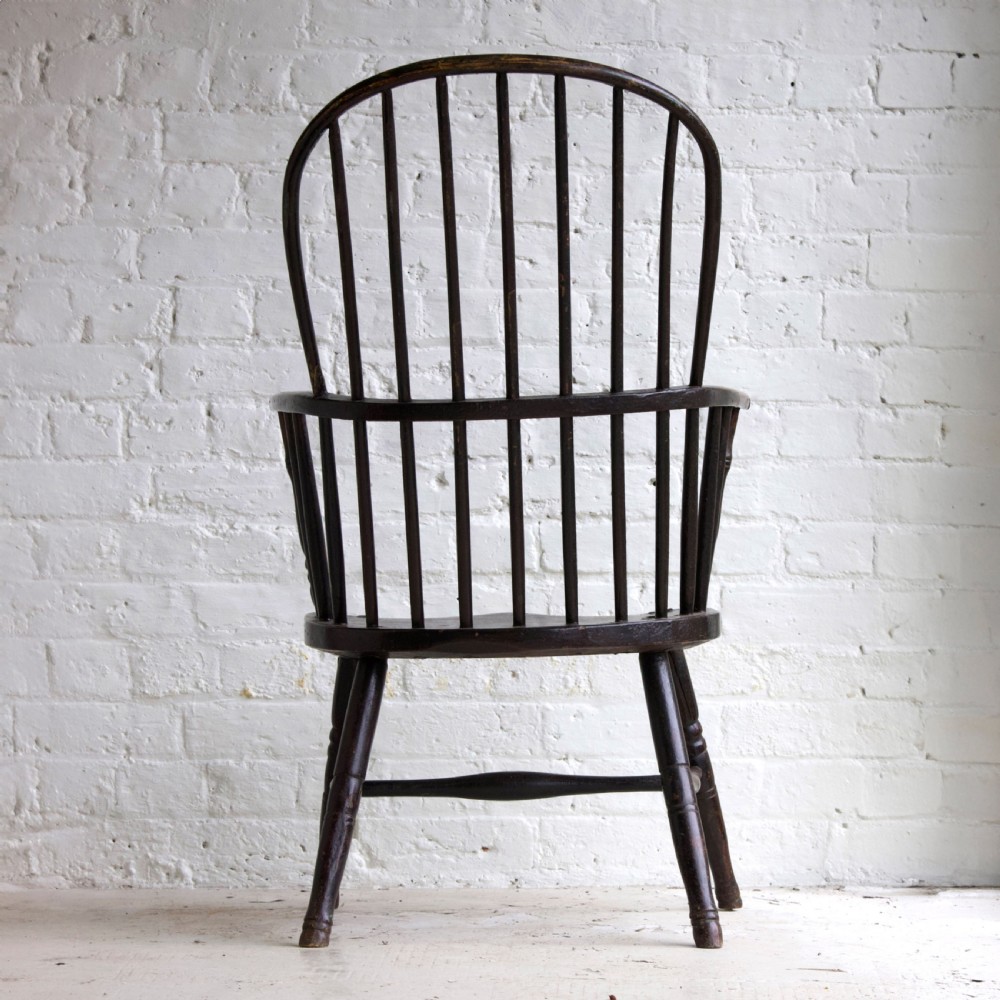 An 18th-century dark brown wooden stickback Windsor armchair featuring a tall curved hoop back, turned legs, and an H-stretcher. View III