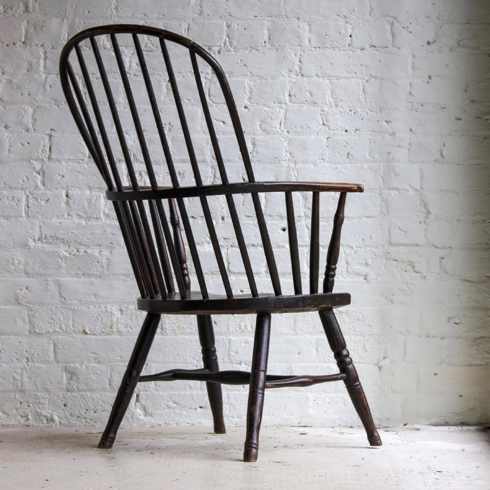 An 18th-century dark brown wooden stickback Windsor armchair featuring a tall curved hoop back, turned legs, and an H-stretcher. View IV