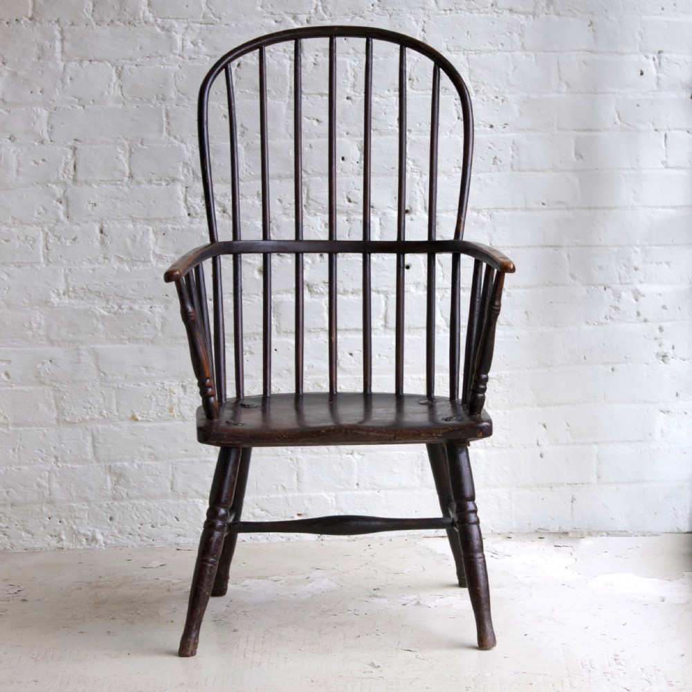An 18th-century dark brown wooden stickback Windsor armchair featuring a tall curved hoop back, turned legs, and an H-stretcher. View V
