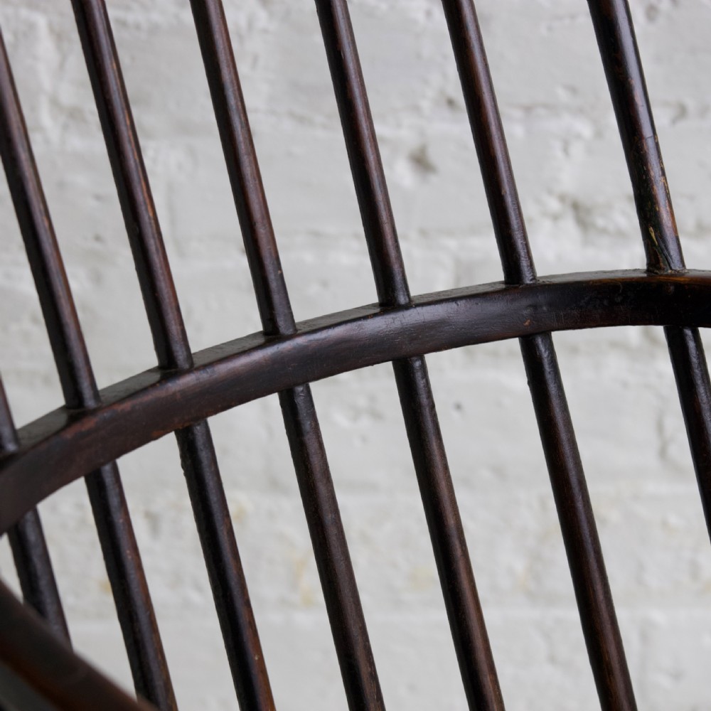 An 18th-century dark brown wooden stickback Windsor armchair featuring a tall curved hoop back, turned legs, and an H-stretcher. View IX
