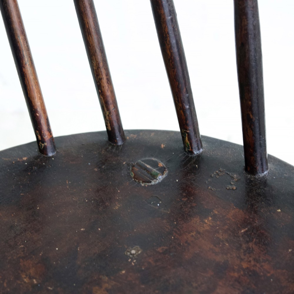 An 18th-century dark brown wooden stickback Windsor armchair featuring a tall curved hoop back, turned legs, and an H-stretcher. View XI