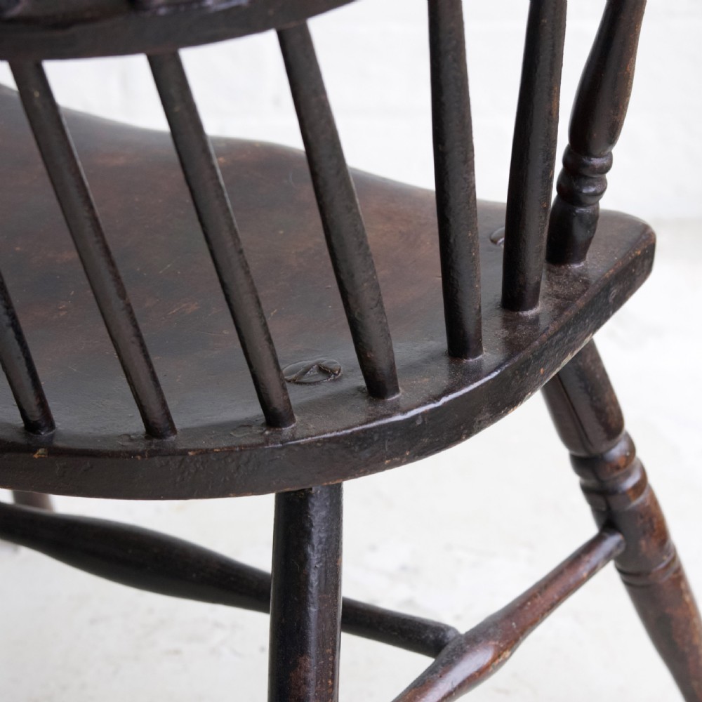 An 18th-century dark brown wooden stickback Windsor armchair featuring a tall curved hoop back, turned legs, and an H-stretcher. View XII