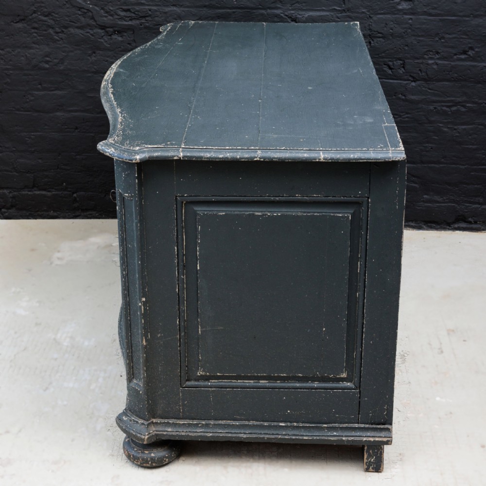 An 18th-century dark green painted serpentine-front chest featuring three drawers and detailed brass keyhole escutcheons. View XIX
