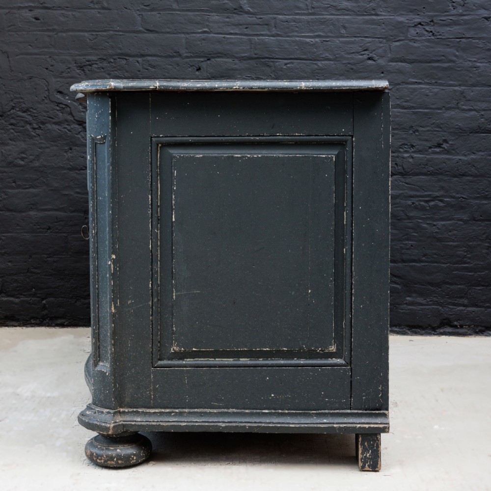 An 18th-century dark green painted serpentine-front chest featuring three drawers and detailed brass keyhole escutcheons. View XX