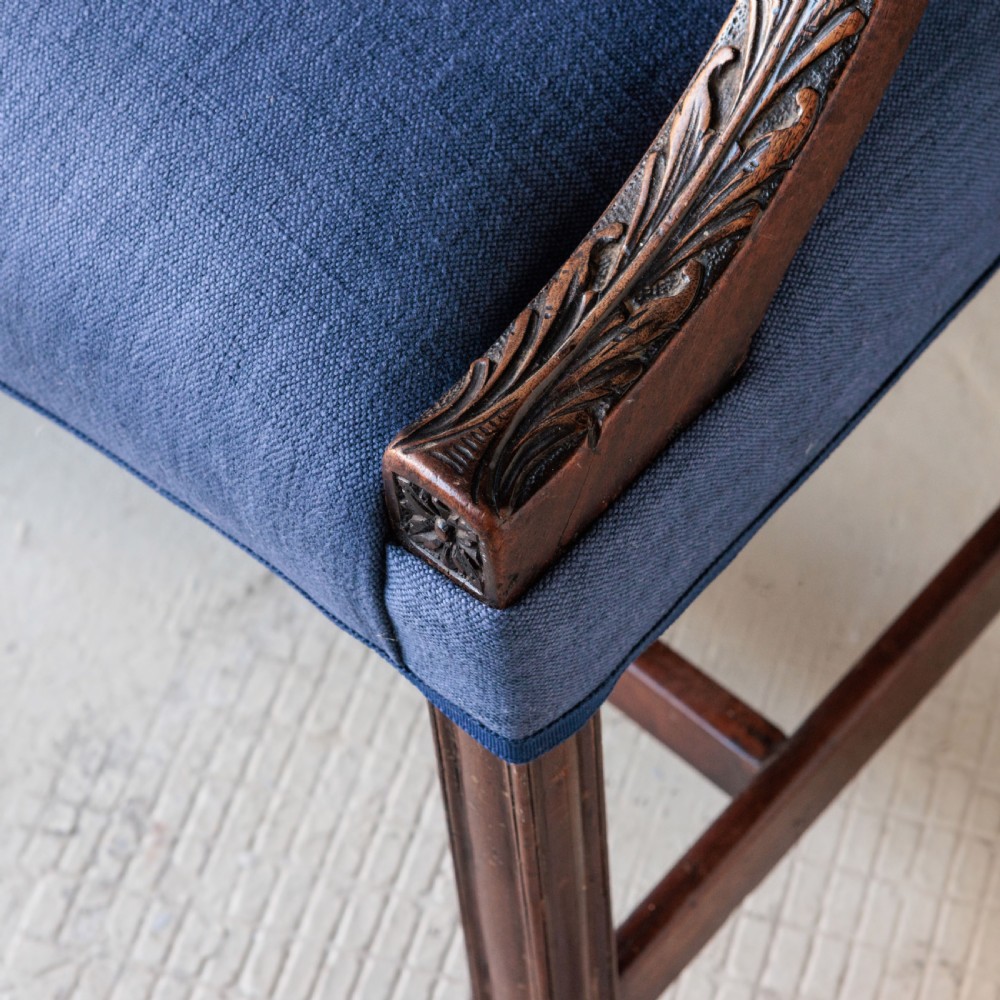 A Georgian Gainsborough armchair with light blue upholstery, carved mahogany arm supports, square stretchered legs, and brass castors. View II