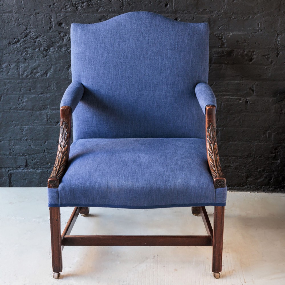 A Georgian Gainsborough armchair with light blue upholstery, carved mahogany arm supports, square stretchered legs, and brass castors. View III