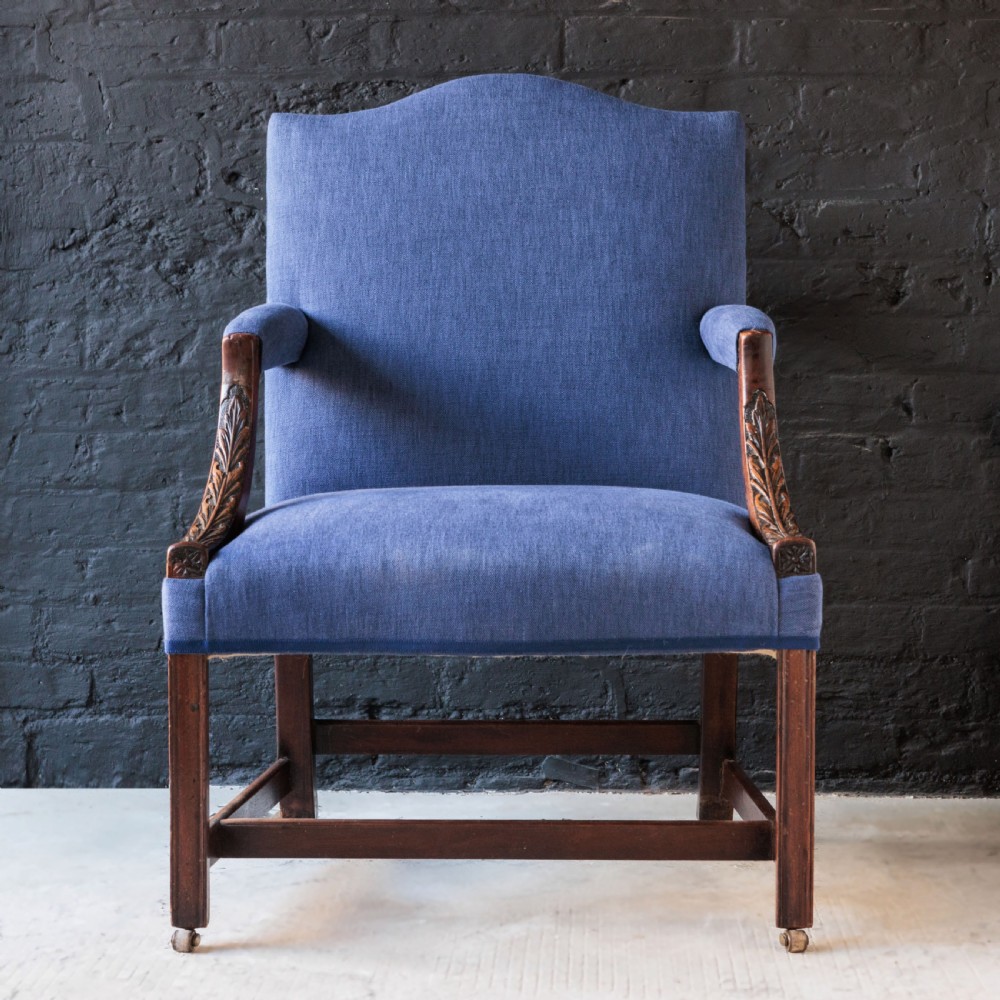 A Georgian Gainsborough armchair with light blue upholstery, carved mahogany arm supports, square stretchered legs, and brass castors. View IV
