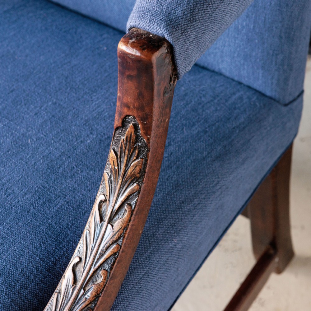 A Georgian Gainsborough armchair with light blue upholstery, carved mahogany arm supports, square stretchered legs, and brass castors. View VI
