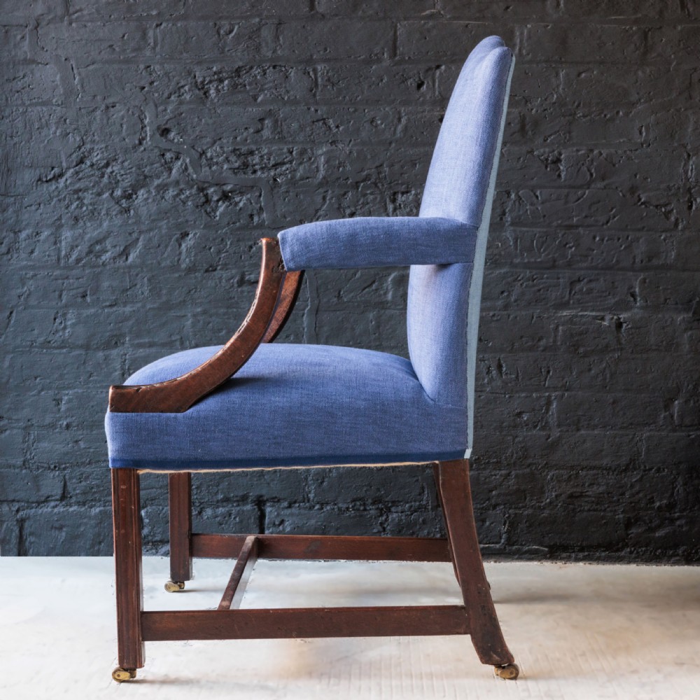 A Georgian Gainsborough armchair with light blue upholstery, carved mahogany arm supports, square stretchered legs, and brass castors. View VIII