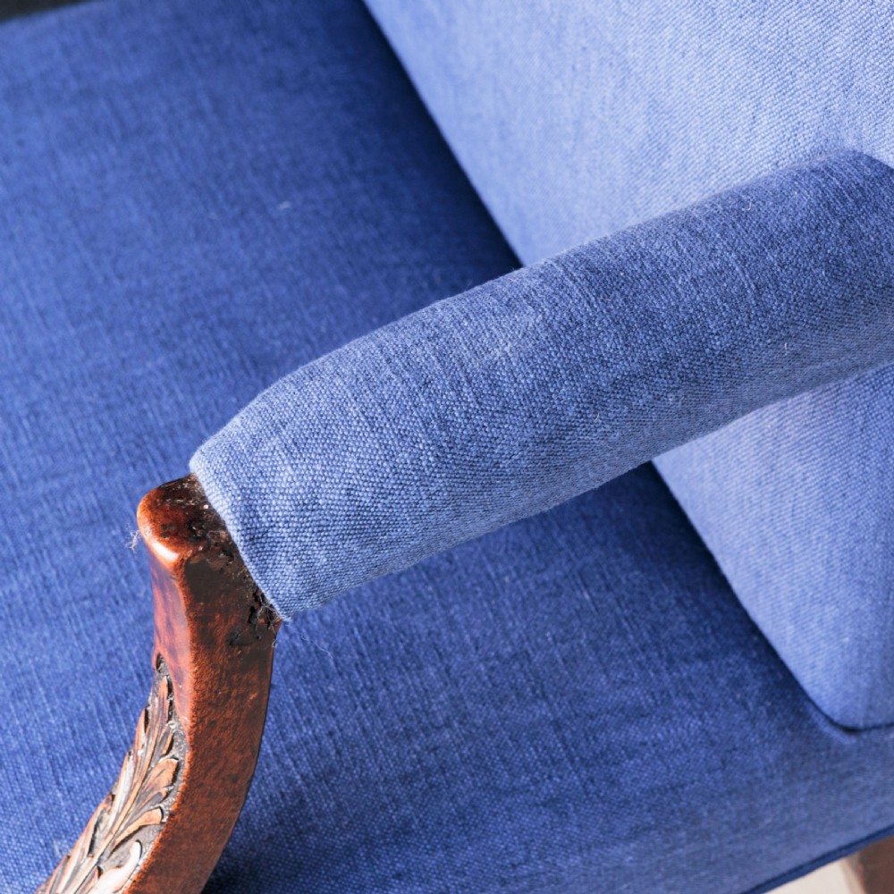 A Georgian Gainsborough armchair with light blue upholstery, carved mahogany arm supports, square stretchered legs, and brass castors. View IX