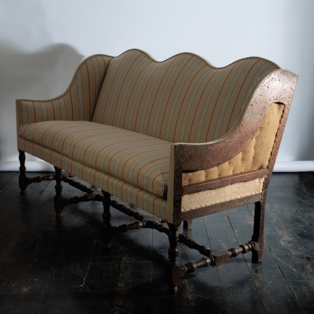 A 17th century wingback sofa featuring striped upholstery, exposed jute side panels, turned wooden legs, and stretchers. View II