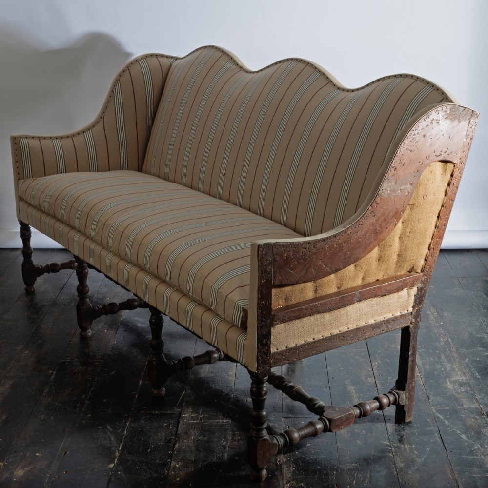 A 17th century wingback sofa featuring striped upholstery, exposed jute side panels, turned wooden legs, and stretchers. View V